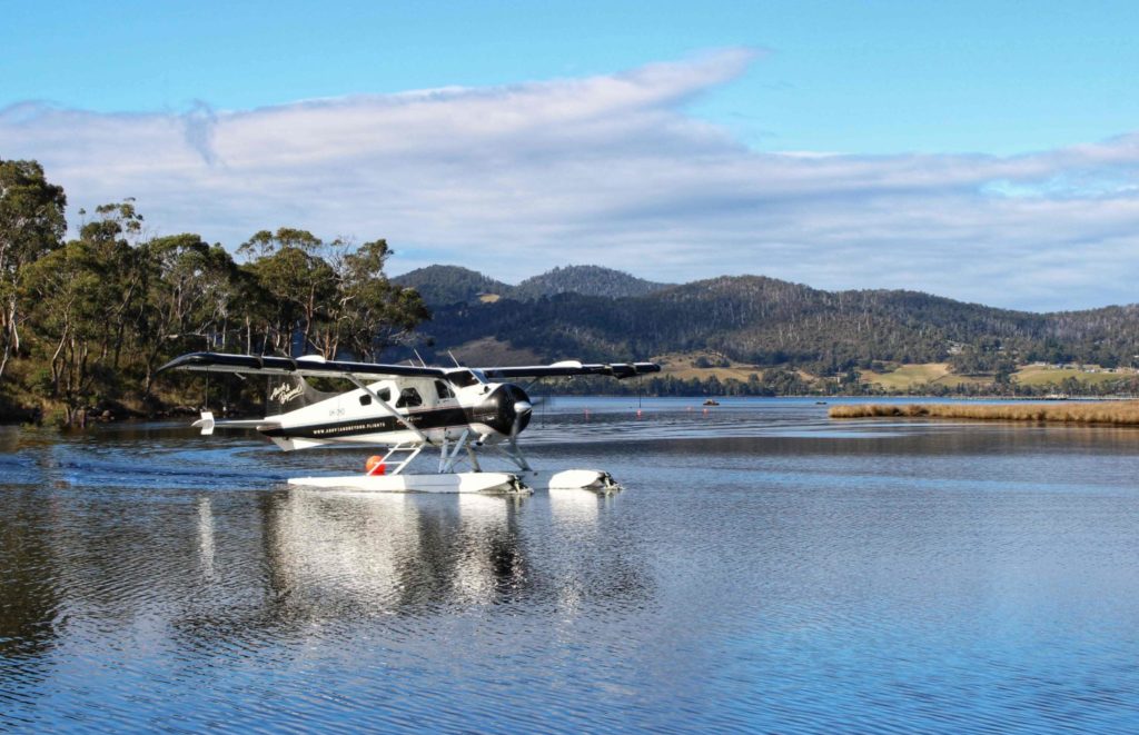 Seaplane on the Huon River. Mountains in the distance, blue sky with clouds